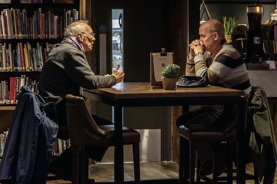 Deux personnes en conversation à une table de bibliothèque